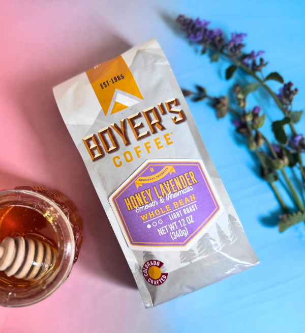 Bag of Boyer's Coffee Honey Lavender Whole Bean with a glass of honey and lavender flowers on a gradient background